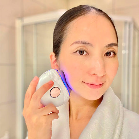 asian woman using AuraLift Gua Sha on jawline